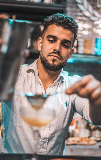 bearded guy straining a cocktail
