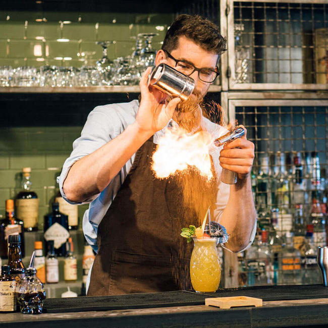 bartender creating fire trick over cocktail