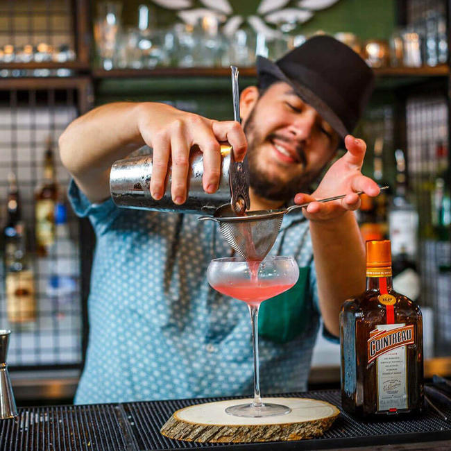 guy in fedora straining a cocktail
